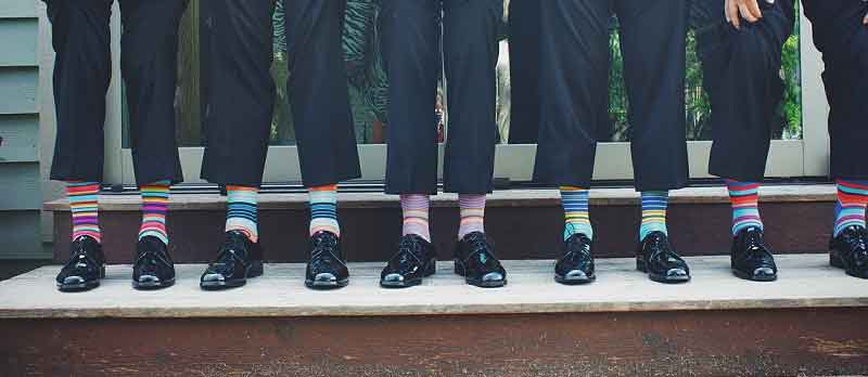 Braeutigam und Trauzeugen in Hochzeitsanzug mit bunten Socken